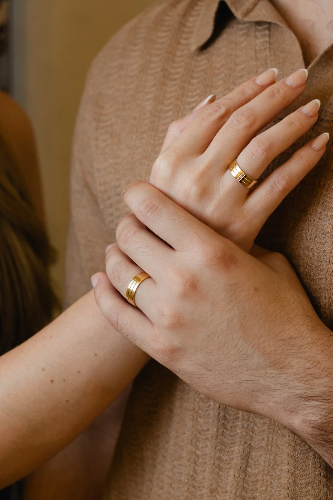Casal com alianças Carnelian em ouro, mãos unidas sobre uma camisa